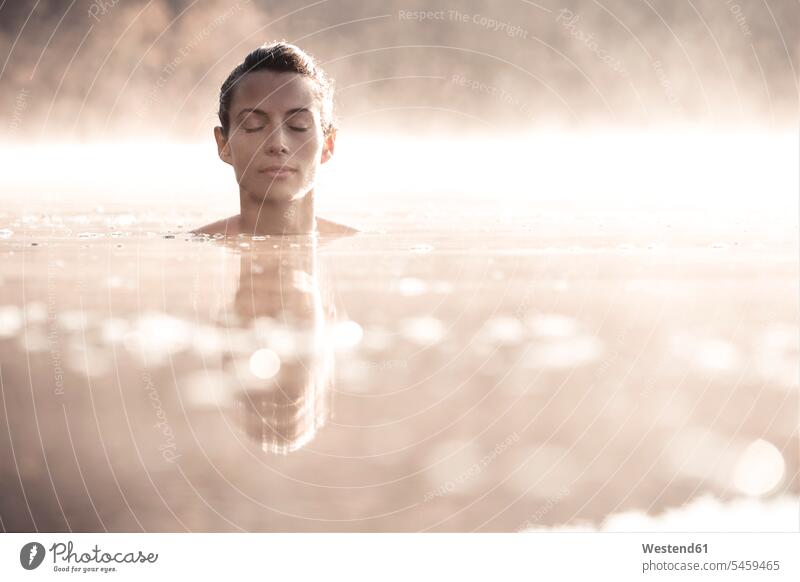 Frau badet im Morgennebel in einem See Badebekleidung Badeanzuege Badeanzüge früh Frühe entspannen relaxen entspanntheit relaxt geniessen Genuss Naesse Nässe