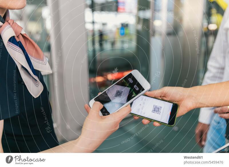 Airline-Mitarbeiter scannt QR-Codes von Passagieren mit Smartphone am Flughafen Flughaefen Flugplätze Airport Flugplaetze Airports Terminals Flugplatz Flughäfen