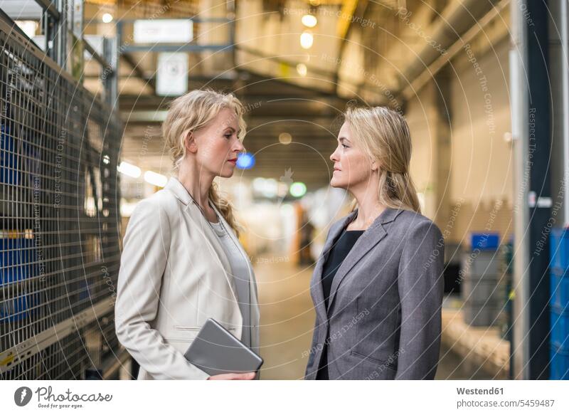 Zwei Frauen stehen sich im Fabriklager gegenüber Lagerhalle Lagerhallen ansehen weiblich Fabrikhalle Industriehallen Fabrikhallen Fabriken Depot schauen sehend