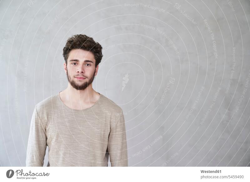 Porträt eines selbstbewussten jungen Mannes vor grauer Wand Portrait Porträts Portraits Zuversicht Zuversichtlich Selbstvertrauen Vertrauen Europäer Kaukasier