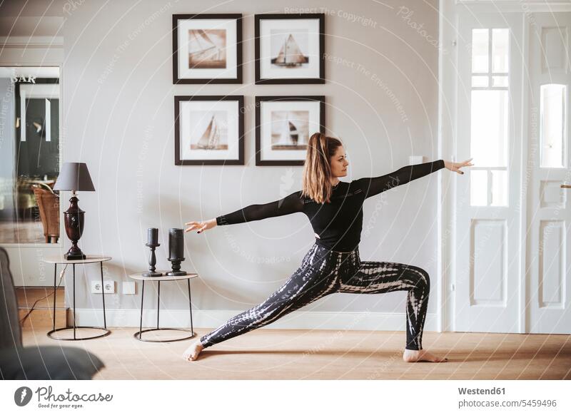 Frau, die zu Hause Yoga praktiziert, Krieger-Pose daheim Muße trainieren bewegen sich bewegen Grund Land außen draußen im Freien drinnen Innenaufnahmen am Tag