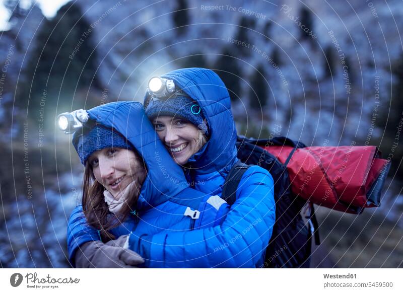 Zwei glückliche junge Frauen mit Stirnlampen umarmen sich in den Bergen weiblich Glück glücklich sein glücklichsein Kopfleuchte Kopflampe Freundinnen