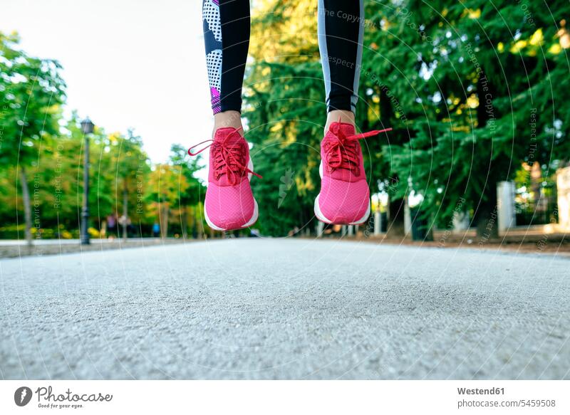 Nahaufnahme von Frauenfüssen mit rosa Laufschuhen beim Springen Farben Farbtoene Farbton Farbtöne pinkfarben leicht Muße fit gesund Gesundheit Jogging Anreiz