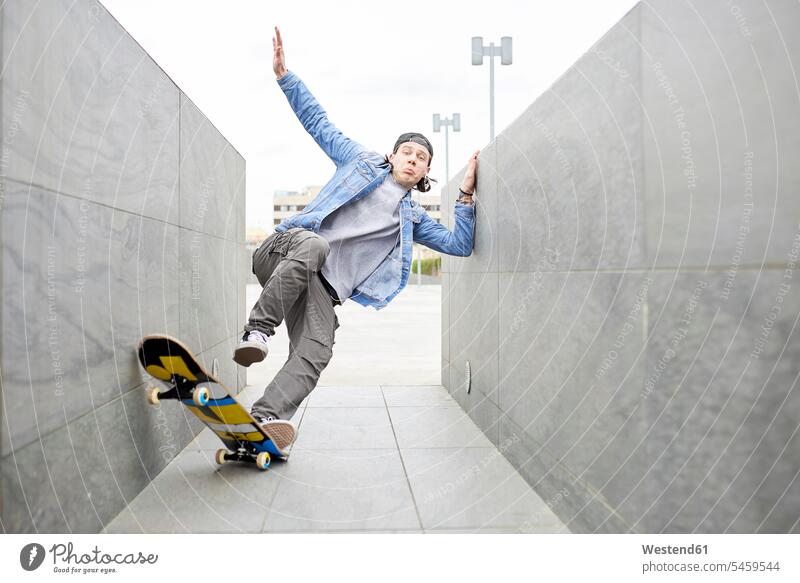 Junger Mann beim Skateboarden in der Stadt balancieren Balance Durchgang junger Mann junge Männer Mauer Mauern cool Coolness Rollbretter Skateboards fallen