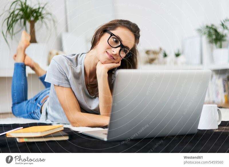 Junge Frau zu Hause auf dem Boden liegend mit Laptop Zuhause Computer Erwachsener Mensch lernen Verbindung Kaffeetasse Internet WLan Laptop benutzen Technologie