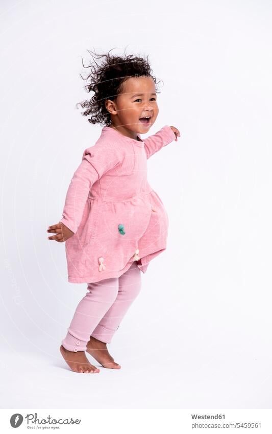 Porträt eines barfüssigen kleinen Mädchens in rosa gekleidet, das vor weissem Hintergrund hüpft Kleider springen Spruenge Sprünge hüpfen freuen Frohsinn