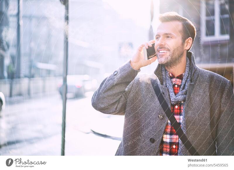Porträt eines lächelnden Mannes am Telefon im Winter Portrait Porträts Portraits telefonieren anrufen Anruf telephonieren Männer männlich Telefon benutzen