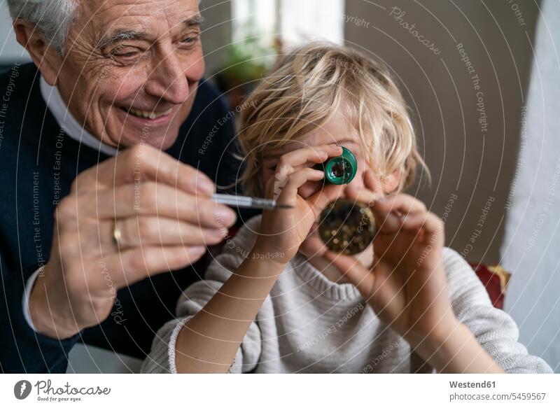 Uhrmacher und sein Enkel prüfen gemeinsam die Uhr Leute Menschen People Person Personen Europäisch Kaukasier kaukasisch 2 2 Menschen 2 Personen zwei