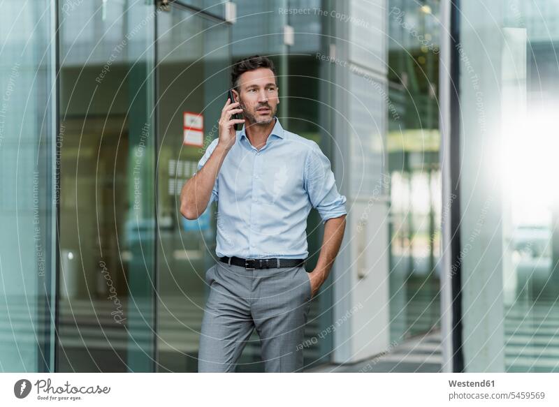 Geschäftsmann am Telefon vor dem Gebäude Job Berufe Berufstätigkeit Beschäftigung Jobs geschäftlich Geschäftsleben Geschäftswelt Geschäftsperson
