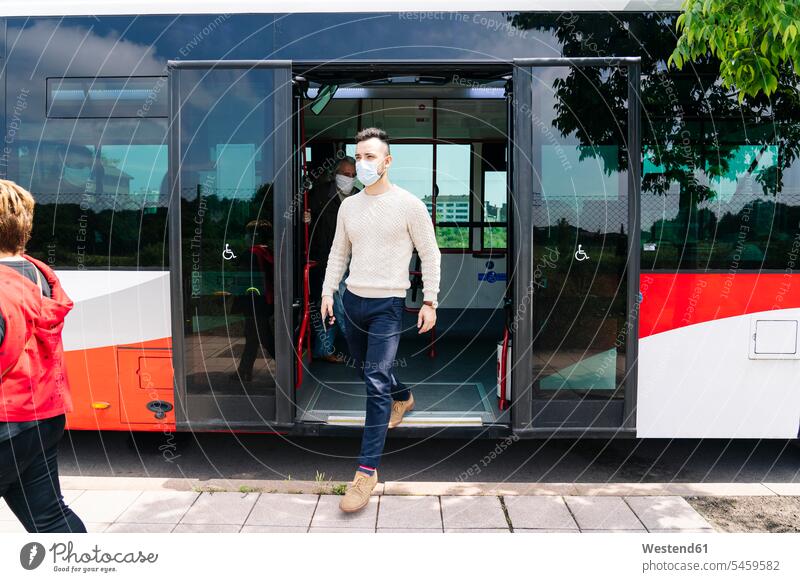 Junger Mann mit Schutzmaske steigt aus öffentlichem Bus aus, Spanien Leute Menschen People Person Personen Europäisch Kaukasier kaukasisch Gruppe von Menschen