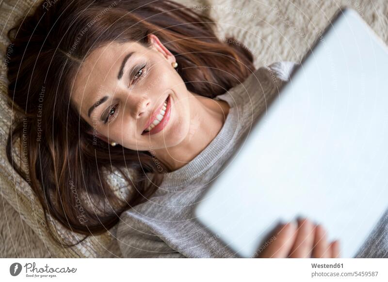 Lächelnde Frau liegt mit einer Tablette auf dem Teppich liegen liegend Tablet Computer Tablet-PC Tablet PC iPad Tablet-Computer Teppiche weiblich Frauen lächeln
