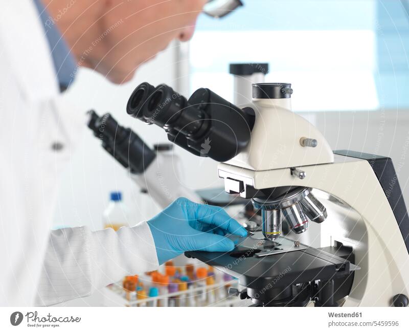 Medizinisches Screening, Wissenschaftler, der einen Objektträger mit einer menschlichen Probe unter einem Mikroskop und einer Blutprobe untersucht Job Berufe