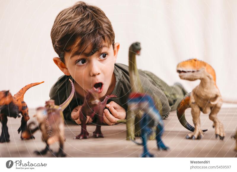 Porträt eines kleinen Jungen, der mit Spielzeugdinosauriern spielt Plastik Gesichtsausdruck Mienenspiel Grimasse schneiden Komisches Gesicht machen Grimassen