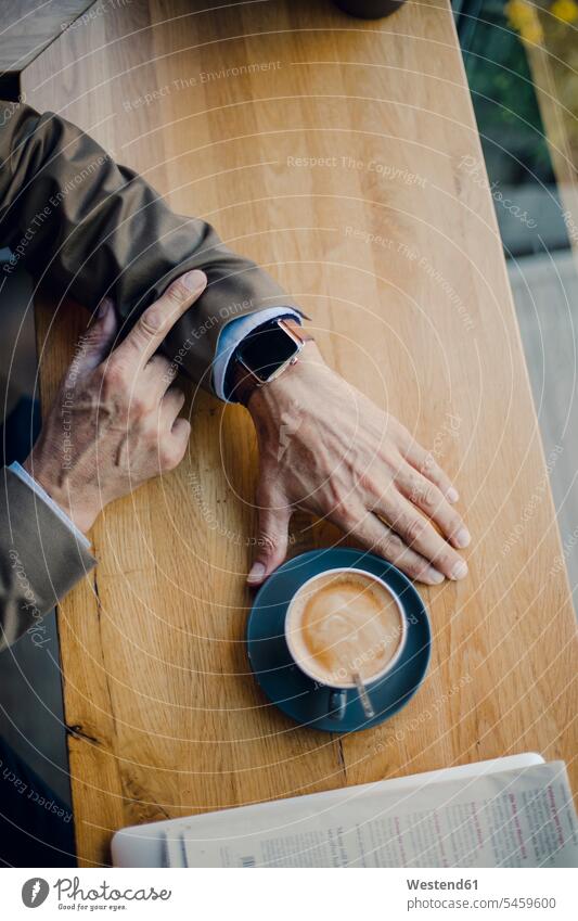 Älterer Geschäftsmann sitzt in einem Café und überprüft die Zeit Kaffee Smartwatch sitzen sitzend trinken Cafe Kaffeehaus Bistro Cafes Cafés Kaffeehäuser