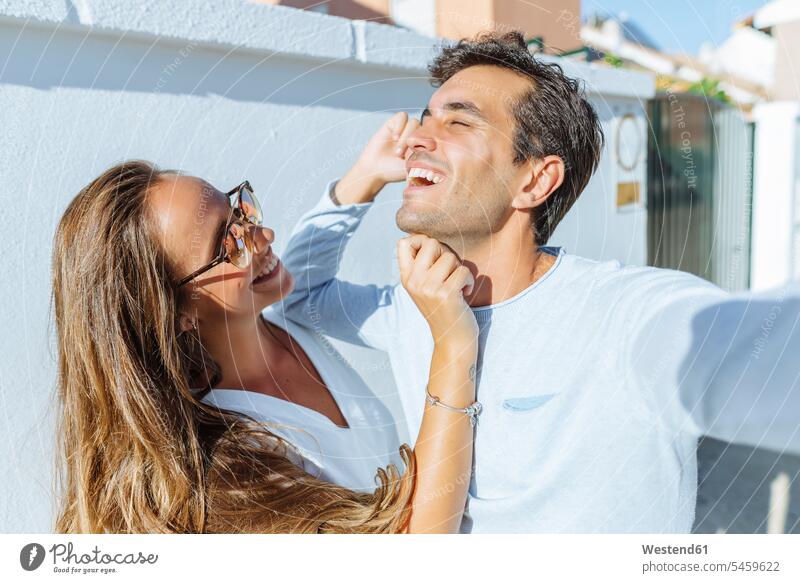 Glückliches verspieltes Paar im Freien an einem sonnigen Tag spielerisch Pärchen Paare Partnerschaft Sonnenlicht glücklich glücklich sein glücklichsein Mensch