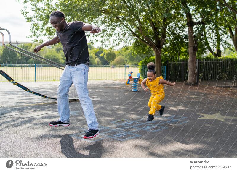 Vater und Tochter beim Hüpfspiel auf einem Spielplatz entspannen relaxen springen Spruenge Sprünge hüpfen Jahreszeiten sommerlich Sommerzeit freuen Frohsinn