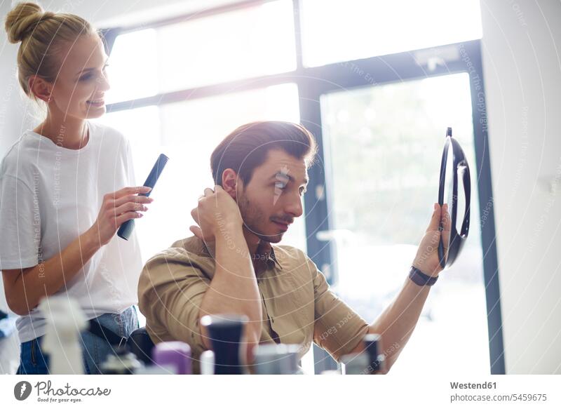 Mann überprüft seinen Haarschnitt beim Friseur Friseursalon Friseursalons Friseurgeschäft Friseurgeschäfte Frisiersalon checken Männer männlich ansehen