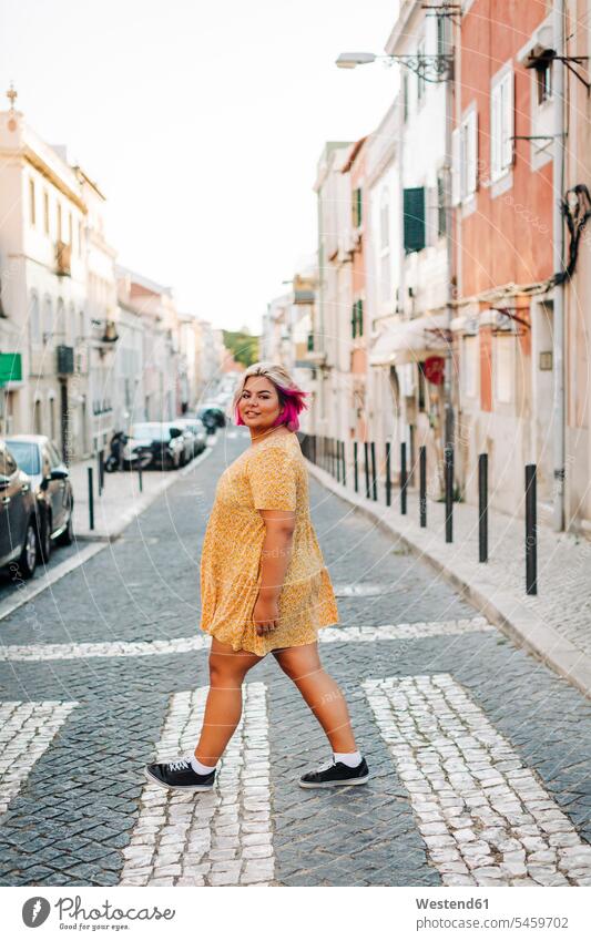 Junge Frau mit positiver Körperhaltung überquert Straße in der Stadt Farbaufnahme Farbe Farbfoto Farbphoto Außenaufnahme außen draußen im Freien Tag