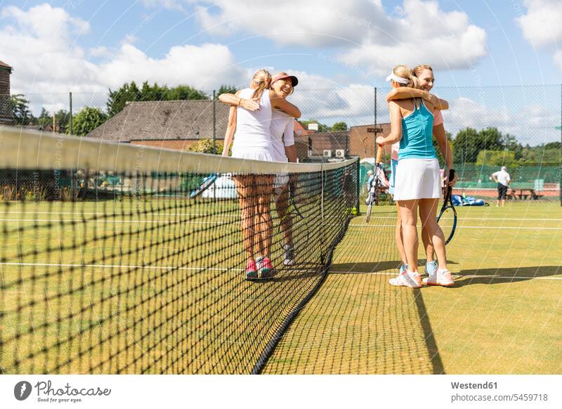 Reife Frauen beenden Tennisspiel auf Rasenplatz umarmen Leute Menschen People Person Personen Europäisch Kaukasier kaukasisch Gruppe von Menschen Menschengruppe
