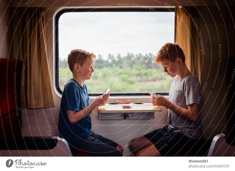 Seitenansicht von Jungen beim Kartenspielen während einer Zugfahrt, Thailand, Asien Farbaufnahme Farbe Farbfoto Farbphoto Spielkarte Spielkarten