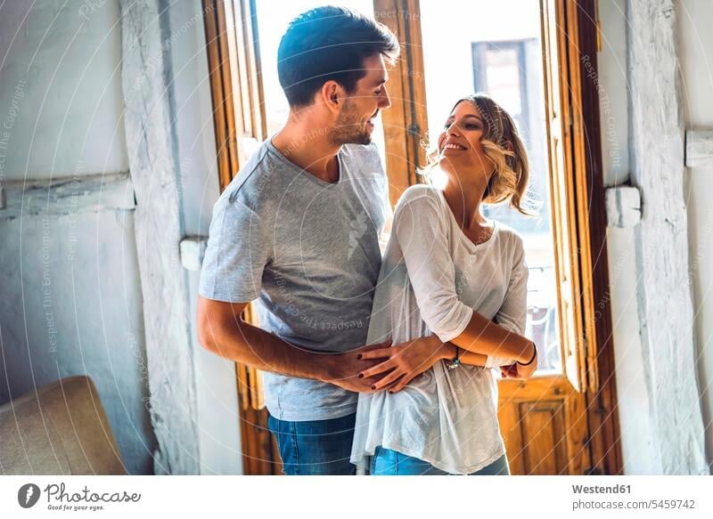 Affectionate junges Paar tanzen im Wohnzimmer zu Hause Arm umlegen Umarmung Umarmungen freuen geniessen Genuss Glück glücklich sein glücklichsein