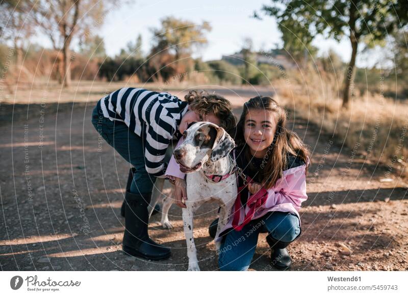 Lächelndes Mädchen und Junge mit Hund am Straßenrand Farbaufnahme Farbe Farbfoto Farbphoto Außenaufnahme außen draußen im Freien Spanien 6-7 Jahre 6 bis 7 Jahre