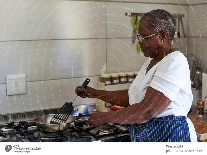 Ältere Frau kocht am Gasherd in der Küche Leute Menschen People Person Personen Afrikanisch Afrikanische Abstammung dunkelhäutig Farbige Farbiger Schwarze 1 Ein