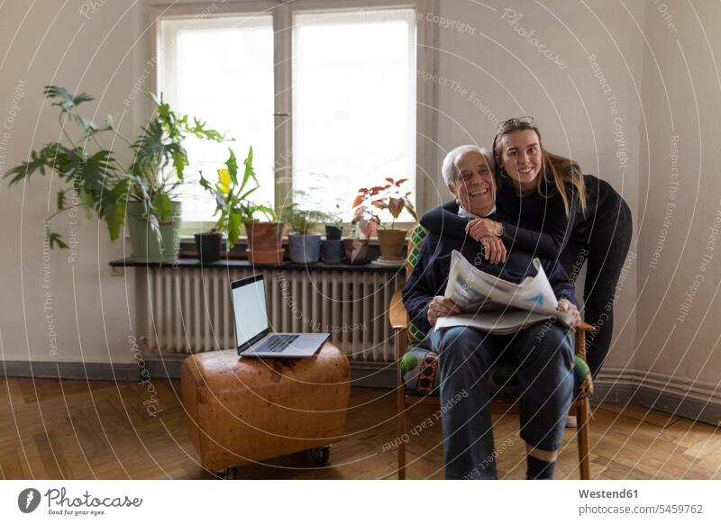 Porträt einer glücklichen jungen Frau und eines älteren Mannes mit Zeitung zu Hause Leute Menschen People Person Personen Europäisch Kaukasier kaukasisch 2