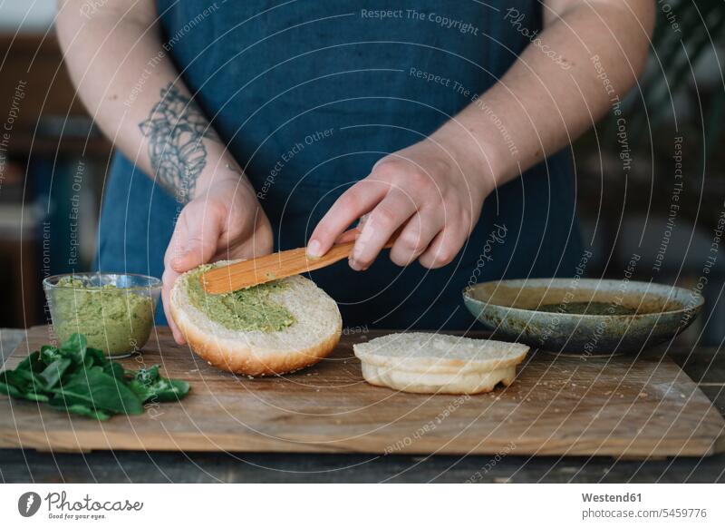 Frau bereitet veganen Burger zu, streicht Avocadocreme auf Brötchen backen kochen vegetarisch Vegetarische Nahrung Vegetarische Ernährung