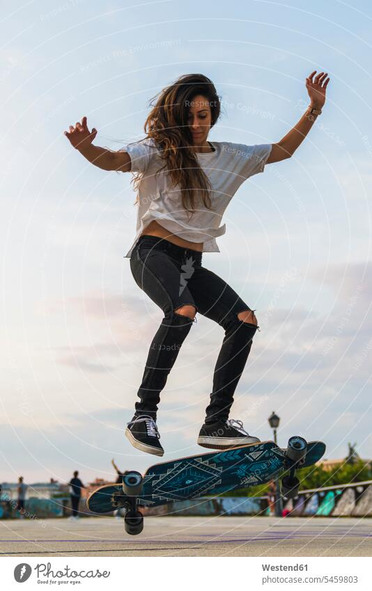 Junge Frau macht einen Skateboard-Trick in der Stadt weiblich Frauen staedtisch städtisch Rollbretter Skateboards Erwachsener erwachsen Mensch Menschen Leute