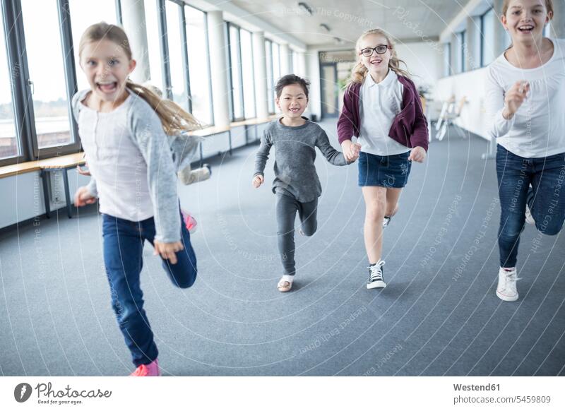 Aufgeregte Schulmädchen eilen den Schulkorridor hinunter Schülerin Schuelerin Schülerinnen Schuelerinnen glücklich Glück glücklich sein glücklichsein Schule