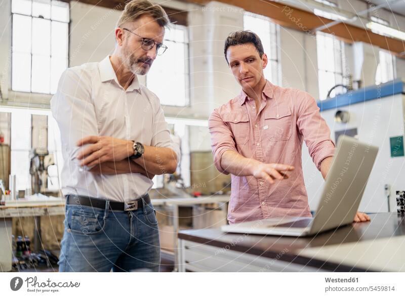 Zwei Kollegen in der Fabrik, die am Laptop diskutieren Arbeitskollegen Geschäftsmann Businessmann Businessmänner Geschäftsmänner besprechen Besprechung Notebook