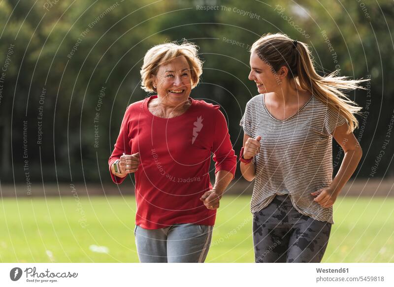 Enkelin und Großmutter haben Spaß, joggen zusammen im Park Grossmutter Oma Grossmama Großmütter Omi Enkeltochter Enkelinnen Enkeltöchter Gemeinsam Zusammen