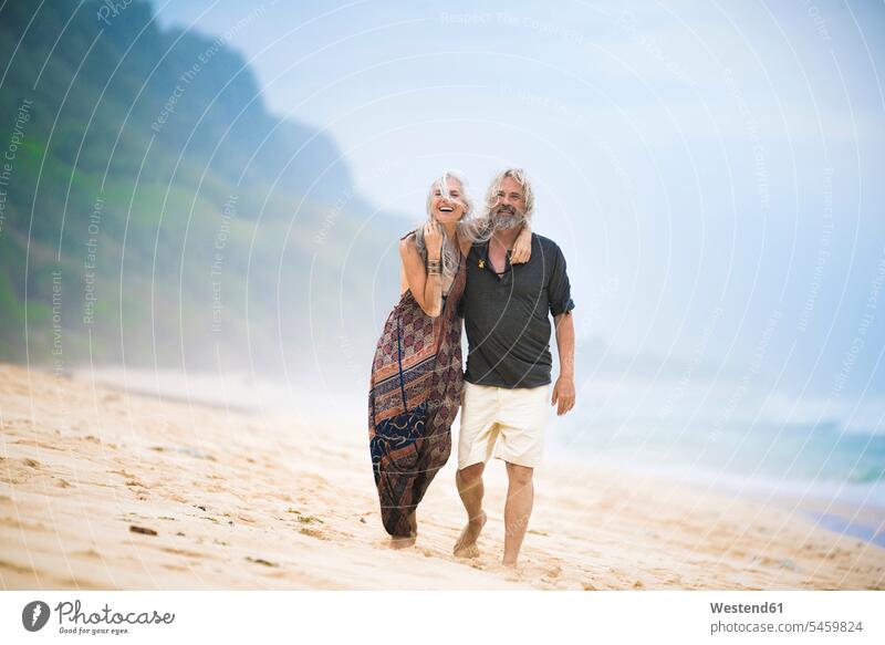 Glückliche Senior Hippie Paar schlendern nebeneinander am Strand Beach Straende Strände Beaches glücklich glücklich sein glücklichsein Seite an Seite