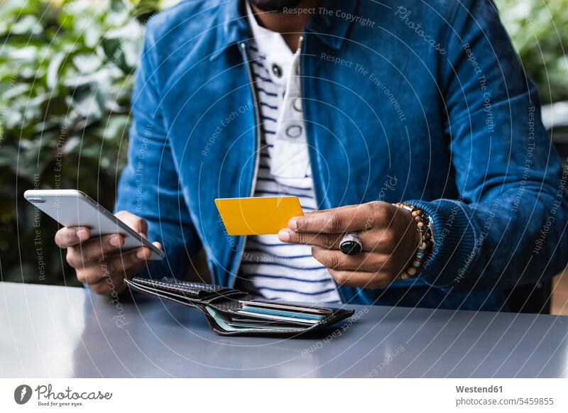 Nahaufnahme eines Mannes mit Kreditkarte beim mobilen Bezahlen in einem Straßencafé Farbaufnahme Farbe Farbfoto Farbphoto Spanien Freizeitkleidung