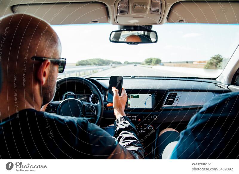 Mann sitzt in einem Auto und benutzt sein Smartphone Leute Menschen People Person Personen Europäisch Kaukasier kaukasisch 1 Ein ein Mensch nur eine Person