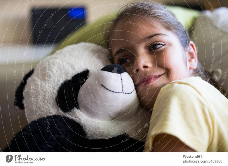 Kleines Mädchen liegt auf der Couch zu Hause kuscheln mit Teddy Panda Bär schmusen knuddeln Koala Koalabären Koalas Kuscheltier Kuscheltiere Zuhause daheim