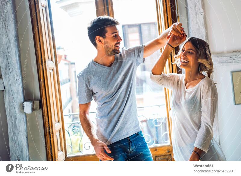 Glückliches junges Paar tanzen am Fenster zu Hause freuen geniessen Genuss glücklich sein glücklichsein leidenschaftlich Leidenschaftlichkeit emotional