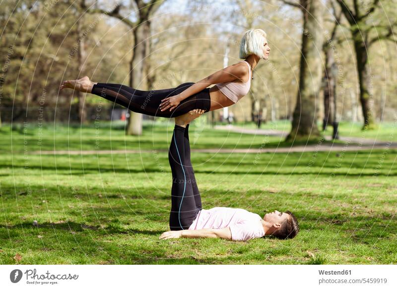 Junges Paar macht Yoga-Akrobatik in einem Stadtpark leicht mühelos Leichtigkeit Training trainieren Freizeitsport Seitenansicht von der Seite Sport Muße