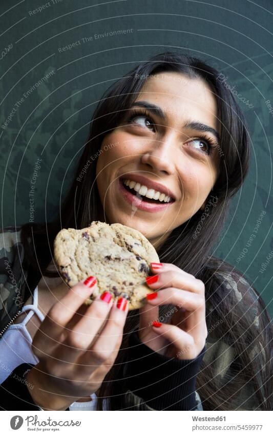 Lächelnde Frau schaut seitwärts und isst Keks Leute Menschen People Person Personen Europäisch Kaukasier kaukasisch 1 Ein ein Mensch eine nur eine Person single