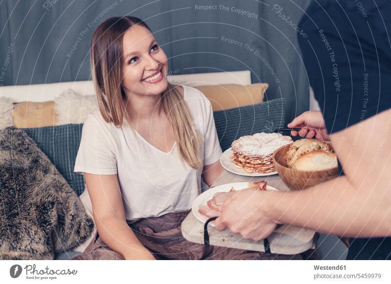 Junger Mann serviert Frühstück im Bett für Freundin Paar Pärchen Paare Partnerschaft Betten frühstücken entspannt entspanntheit relaxt Mensch Menschen Leute
