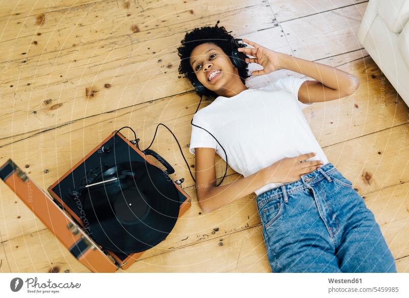 Junge Frau hört zu Hause Vinyl-Schallplatten, liegt am Boden Musik hören Plattenspieler Kopfhörer Kopfhoerer junge Frau junge Frauen analog Medien Medium