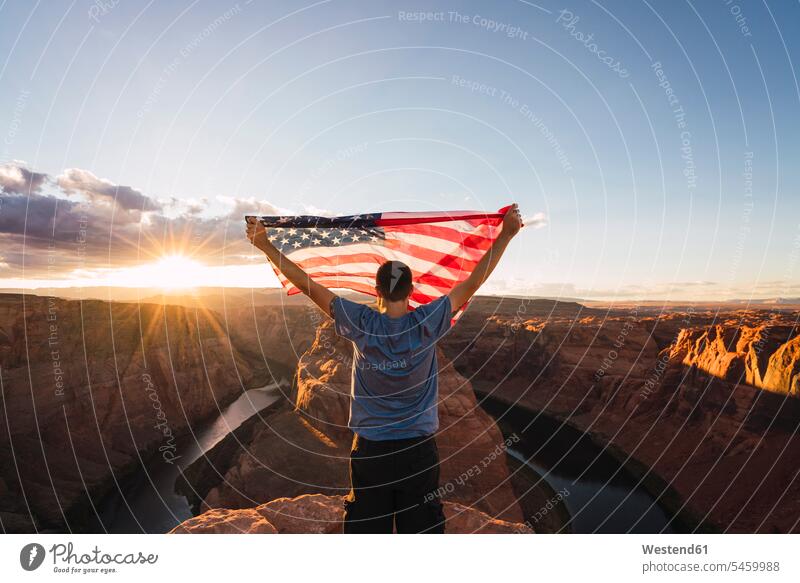 USA, Arizona, Colorado River, Horseshoe Bend, junger Mann auf Aussichtspunkt mit amerikanischer Flagge Männer männlich Reisende Reisender Identität Identitaet