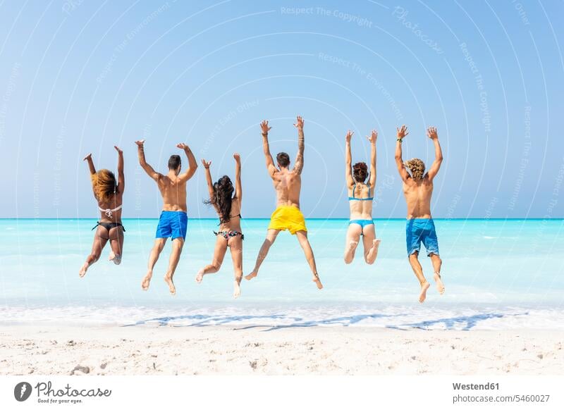 Gruppe von Freunden am Strand, die vor Freude springen Spaß Spass Späße spassig Spässe spaßig Meer Meere Beach Straende Strände Beaches hüpfen aktiv Gewässer