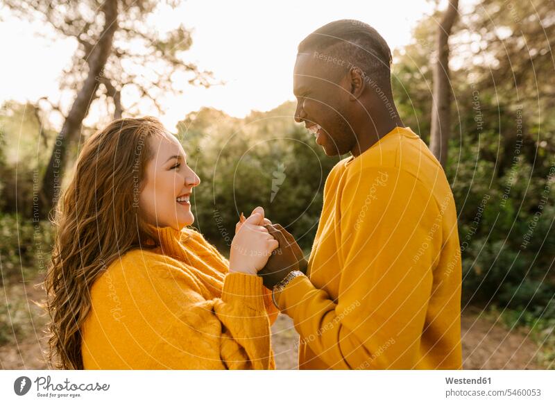 Glückliches Paar hält sich an den Händen, während es im Wald steht Farbaufnahme Farbe Farbfoto Farbphoto Außenaufnahme außen draußen im Freien Spanien