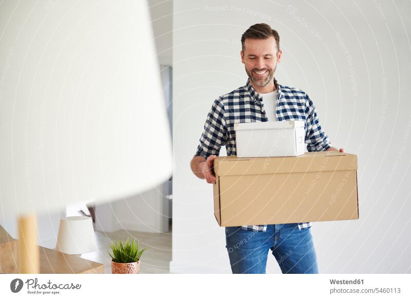Glücklicher Mann zieht in neuen flachen Tragekarton glücklich glücklich sein glücklichsein Männer männlich Wohnung wohnen Wohnungen tragen transportieren