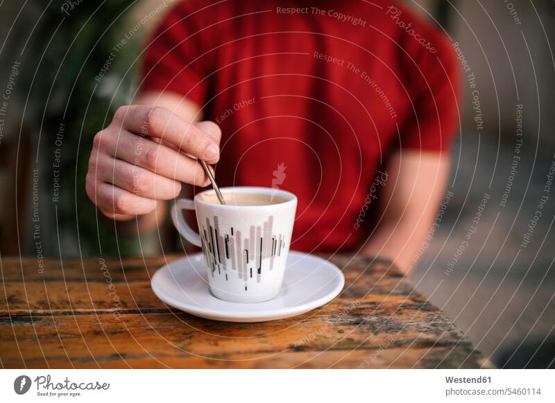 Nahaufnahme der Hand eines Mannes, der Kaffee rührt, während er im Straßencafé sitzt Farbaufnahme Farbe Farbfoto Farbphoto Außenaufnahme außen draußen im Freien