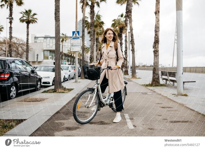 Lächelnde Frau mit E-Bike auf einer Promenade Promenaden eBikes E-Bikes Elektrofahrrad Elektrorad Fahrrad Fahrräder Räder Rad lächeln weiblich Frauen Raeder