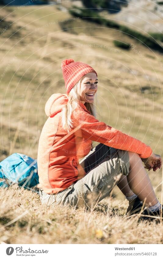 Österreich, Tirol, lächelnde Frau auf Almwiese sitzend weiblich Frauen sitzt Bergwiese Bergwiesen Erwachsener erwachsen Mensch Menschen Leute People Personen