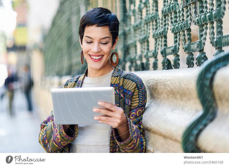 Lächelnde modische junge Frau mit Tablet im Freien Zaun Zäune Tablet Computer Tablet-PC Tablet PC iPad Tablet-Computer Model Modell Modelle Models positiv
